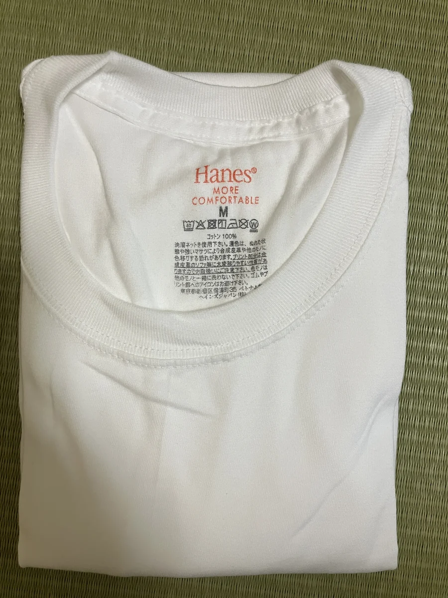 ヘインズの白Tシャツに印字されたMORE COMFORTABLE、M、コットン100％の表示